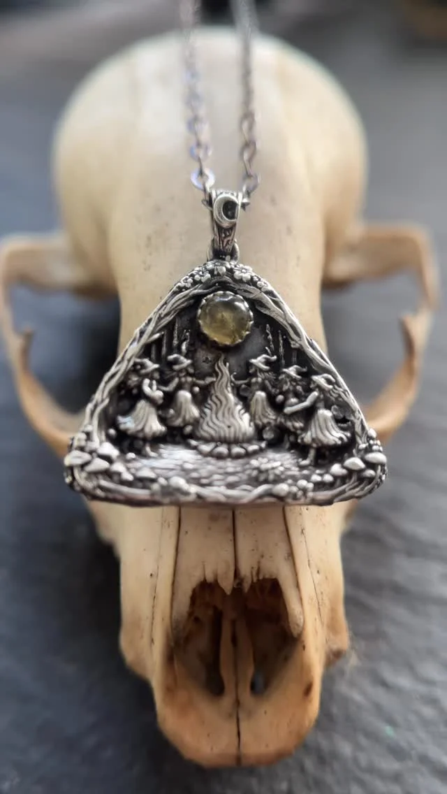 Five witches dance around a blazing bonfire beneath a citrine cabochon in this Walpurgisnacht pendant.

The back features a brass crescent moon, echoing the night sky of the witches’ gathering.

Walpurgisnacht, celebrated on the night of April 30, is the legendary “Night of the Witches” in German folklore, when witches were said to gather on mountaintops and dance around sacred fires to welcome the arrival of spring.